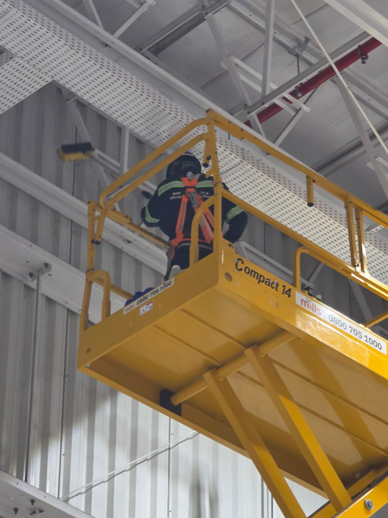 Profissional da Marvix em limpeza industrial em altura com plataforma elevatória